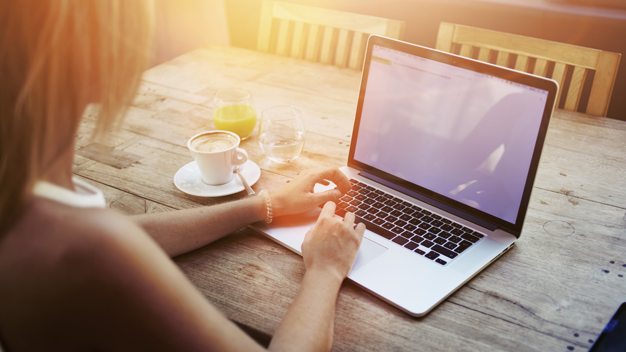 Sunlit woman sitting outside on laptop