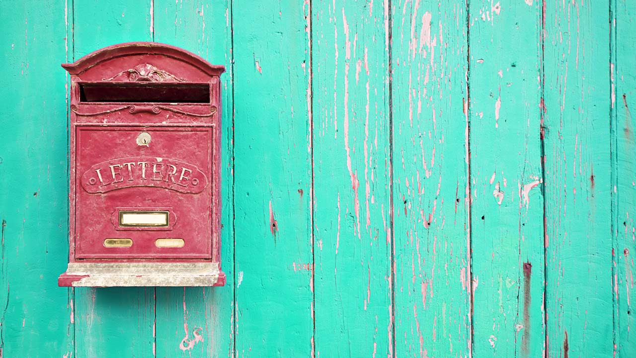 Vintage red mailbox over a green wood wall